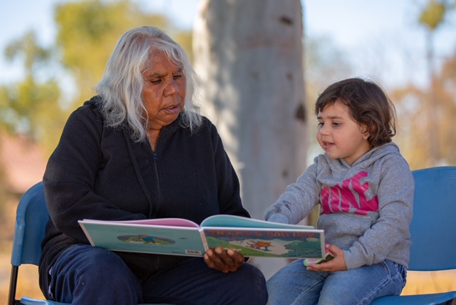 Graduate Joyce (left) shares a book. 